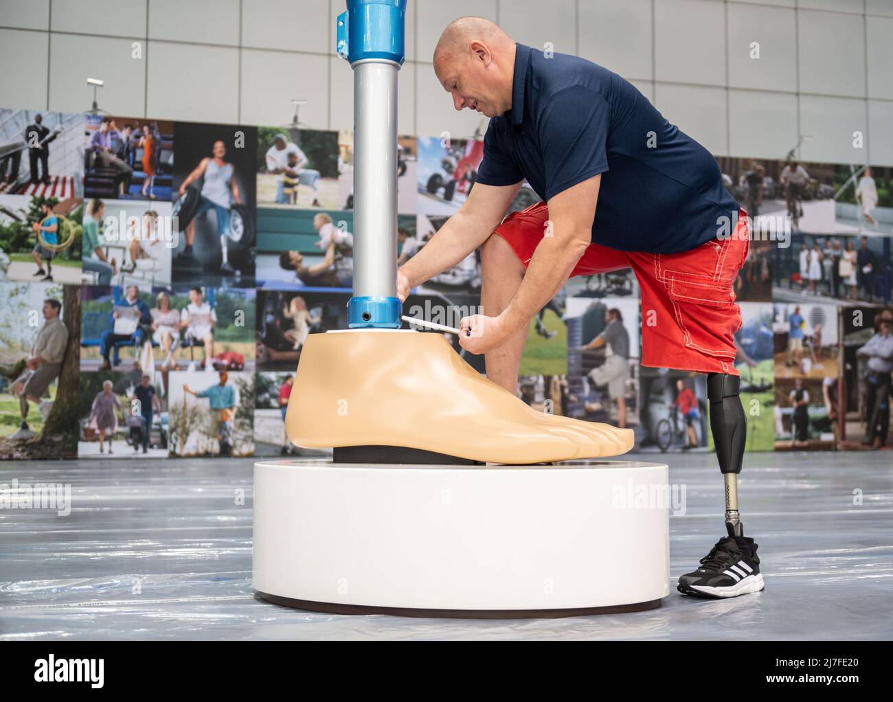 Leipzig, Germany. 09th May, 2022. Mathias Börner, Ottobock sales representative for Saxony and Thuringia, screws on an oversized model of a leg prosthesis. The Duderstadt-based company Ottobock is displaying a four-meter-high model of the C-Leg leg prosthesis to mark its 25th anniversary at OTWorld 2022, the world's leading trade fair for orthopaedic and rehabilitation technology. It was the world's first mechatronic knee joint. The C-Leg technology has now been used in more than 100,000 fittings worldwide. Credit: Christian Modla/dpa/Alamy Live News Stock Photo