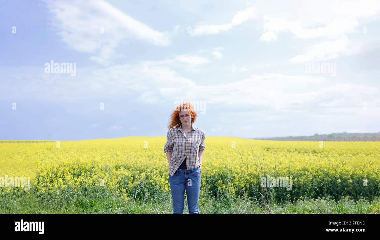 A woman in a country outfit standing in a yellow field on sunny summer day Stock Photo