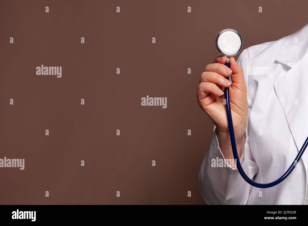 Doctor hand holding stethoscope on brown background Stock Photo
