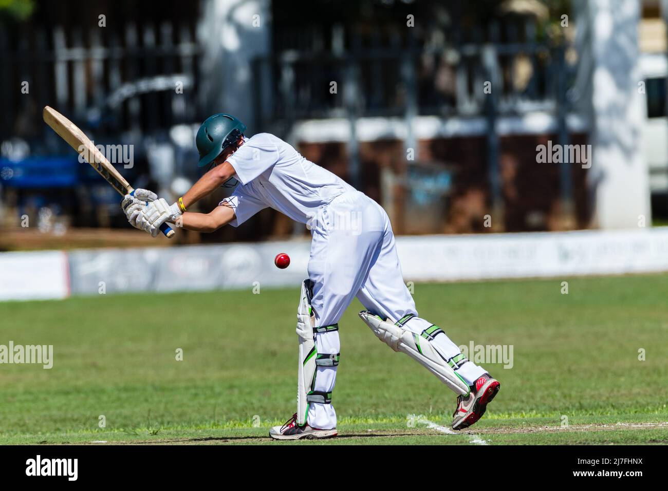 Cricket batsman unrecognizable plays red ball delivered by bowler