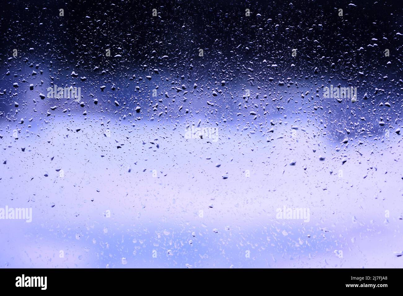 blue background water drops on the glass. wet window glass with ...