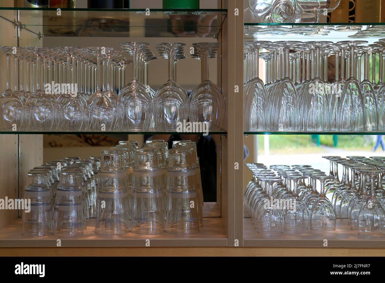 Many shiny glasses in rows on shelves inside a bar Stock Photo