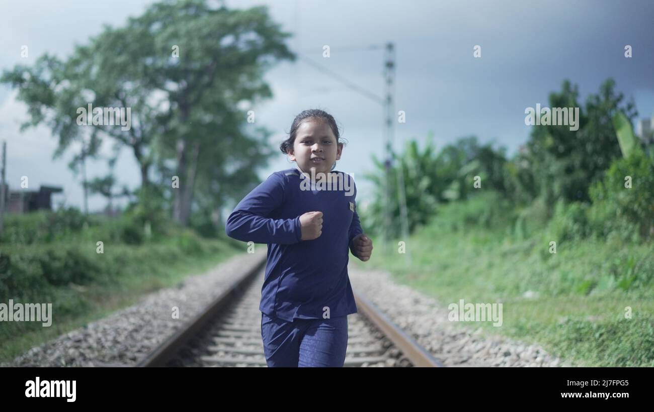 Indian Kid running on the railway track in the Himalayan range of India, greenery in the background. Physical fitness training. High-quality photo Stock Photo