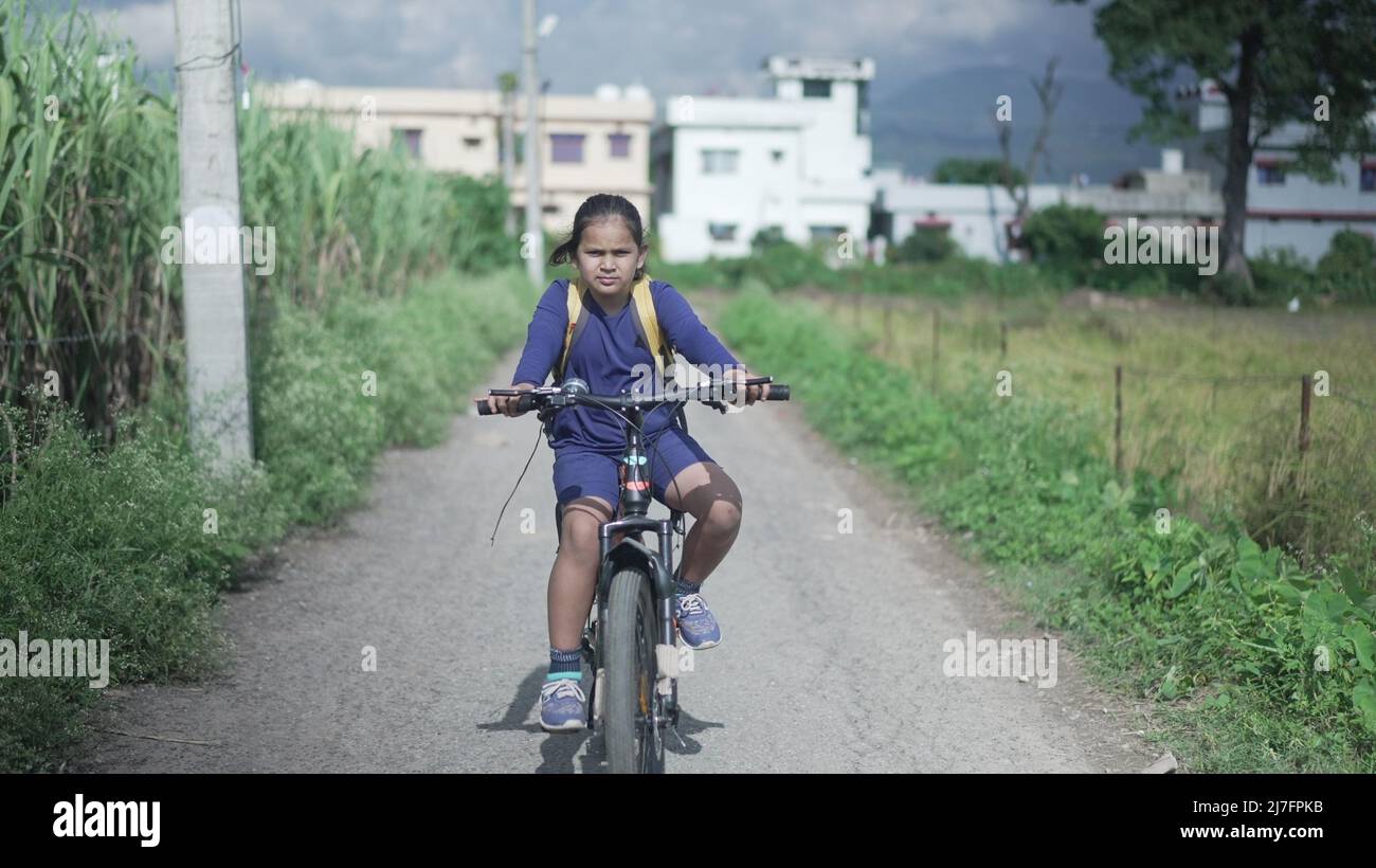 An Indian Kid cycling on a road, near a sugarcane field in a rural area of Uttarakhand, India. Physical fitness of an Indian boy. High-quality image. Stock Photo