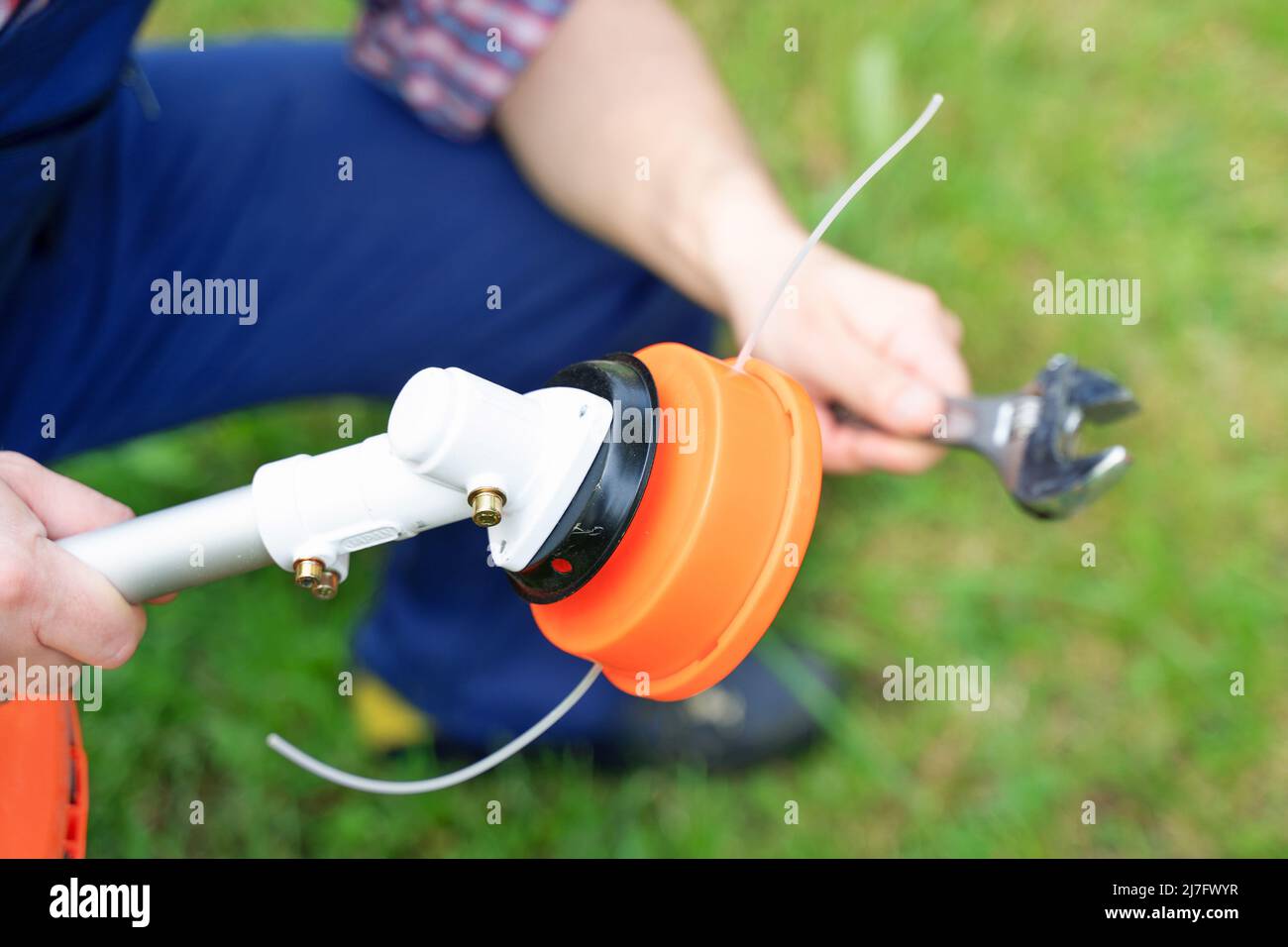 One gardener mowing grass fixing brushcutter problem Stock Photo Alamy