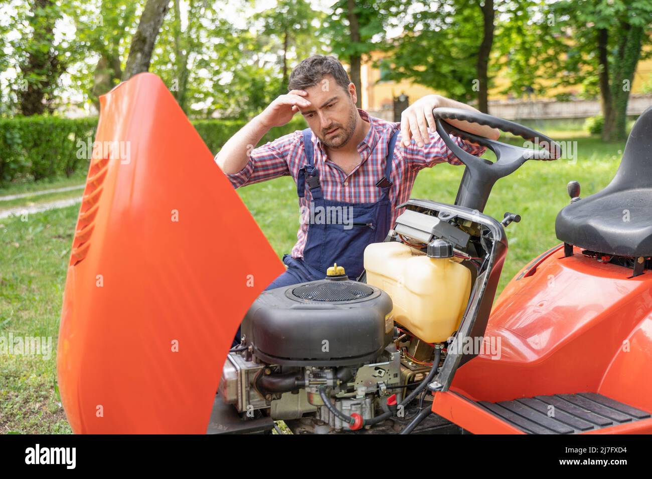 One gardener mowing grass fixing lawn mower engine problem Stock Photo Alamy