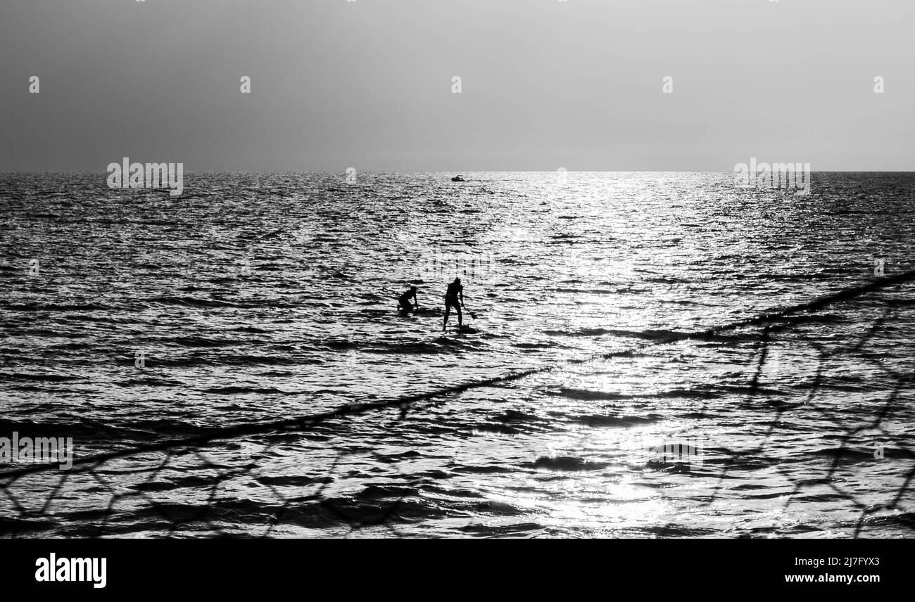 Couple riding stand up paddle in Gaeta, Lazione (Italy), at sunset Stock Photo