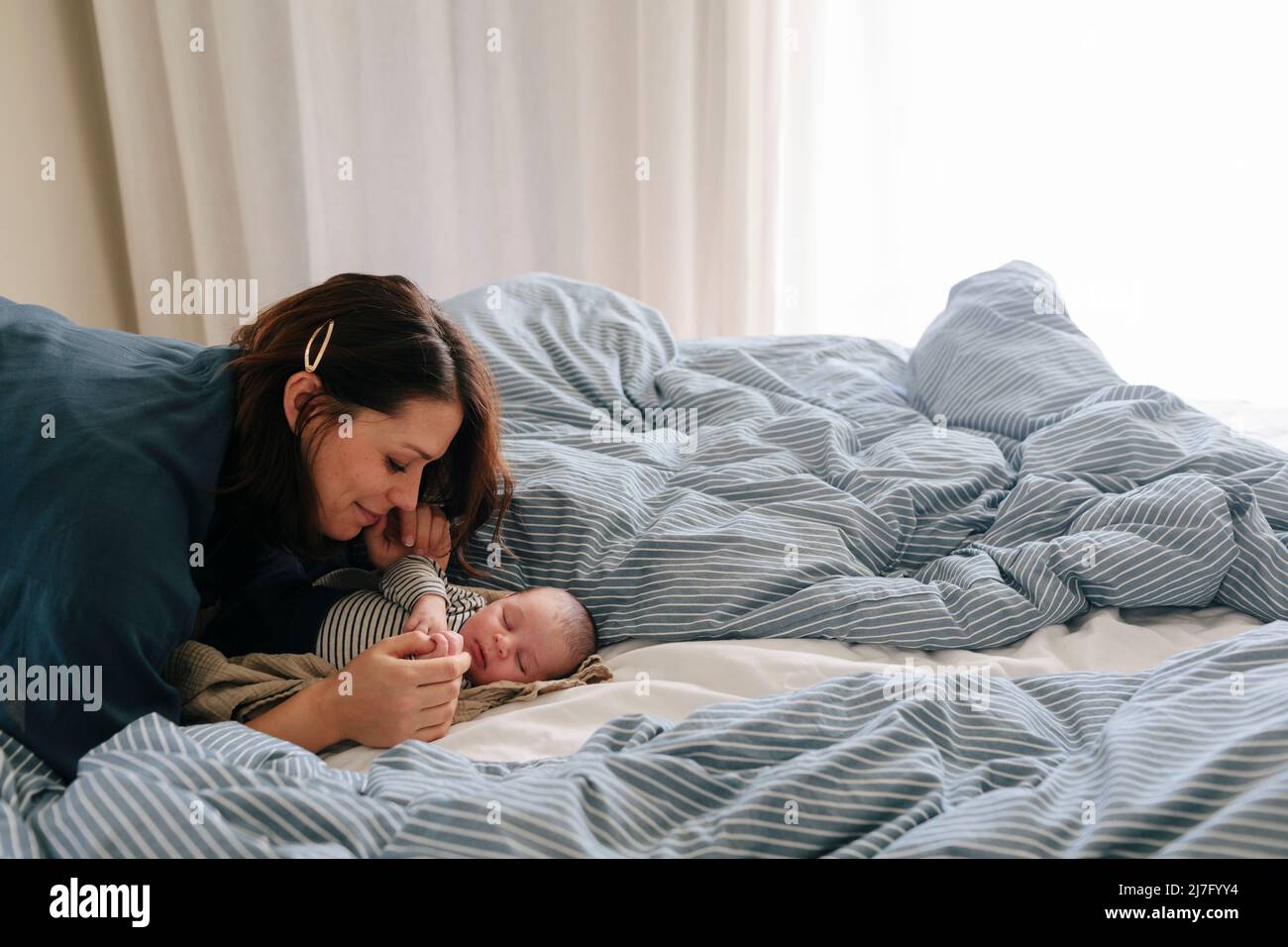 Mother cuddling newborn baby in bed Stock Photo Alamy