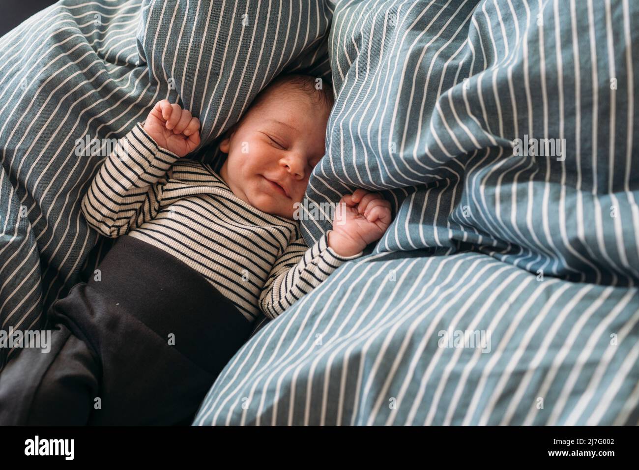 Sleeping newborn baby lying in bed Stock Photo