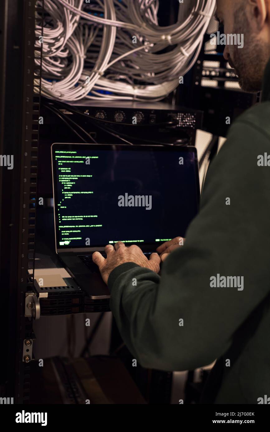 IT technician working on laptop in server room Stock Photo