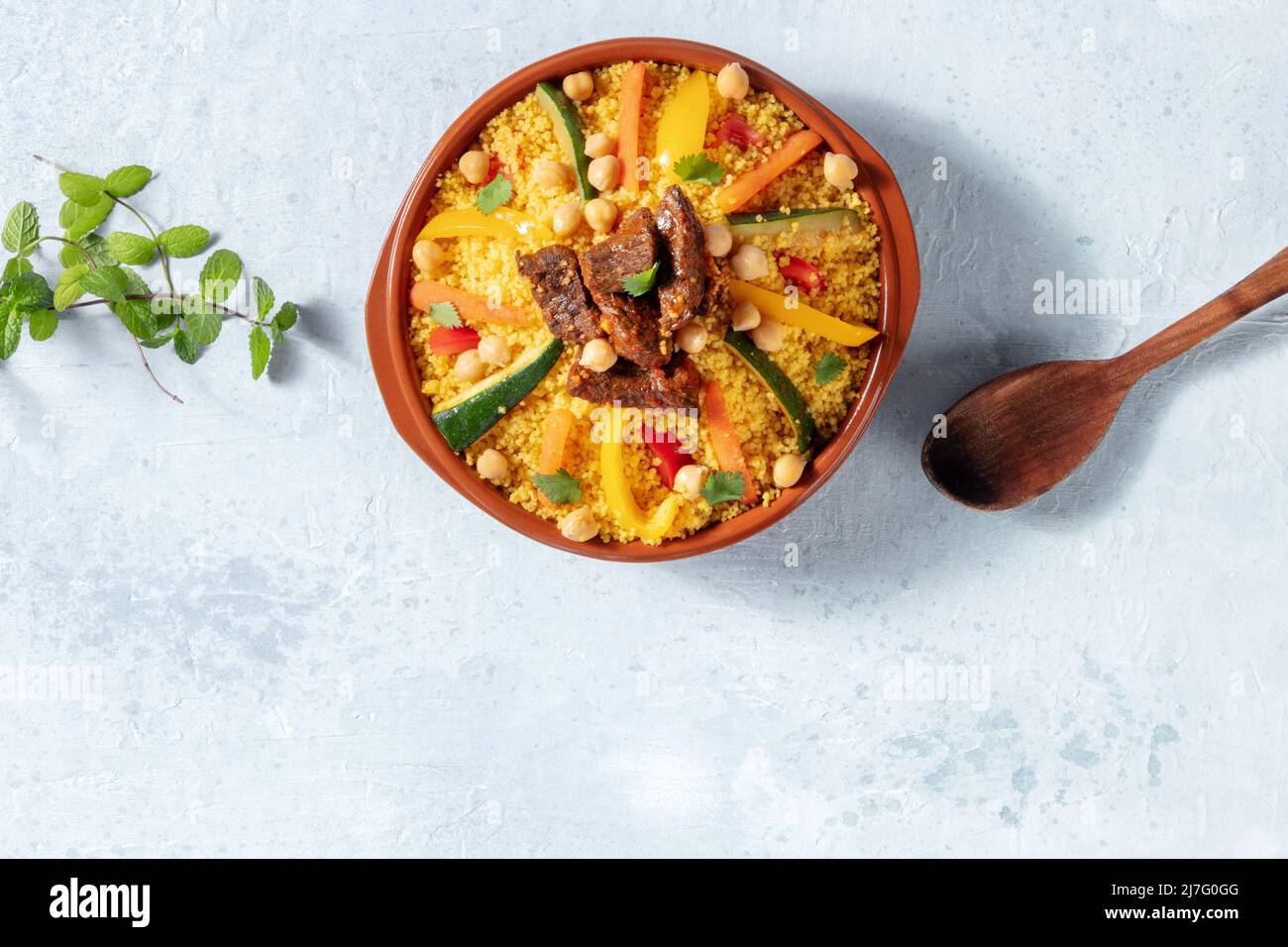 Meat and vegetable couscous, traditional Moroccan food, shot from the top, with fresh herbs and a place for text Stock Photo