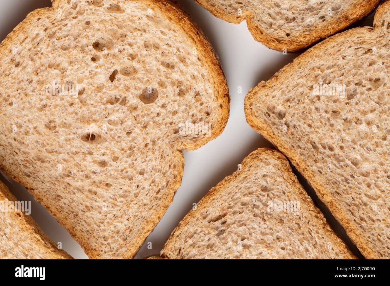 Slices of brown bread baked from wheat flour on a white plate. Stock Photo