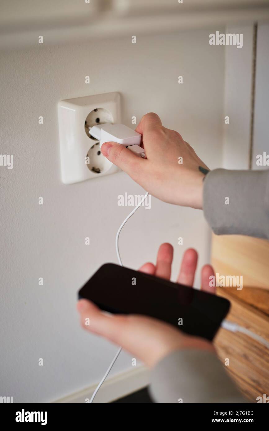 Hands plugging in cell phone charger Stock Photo