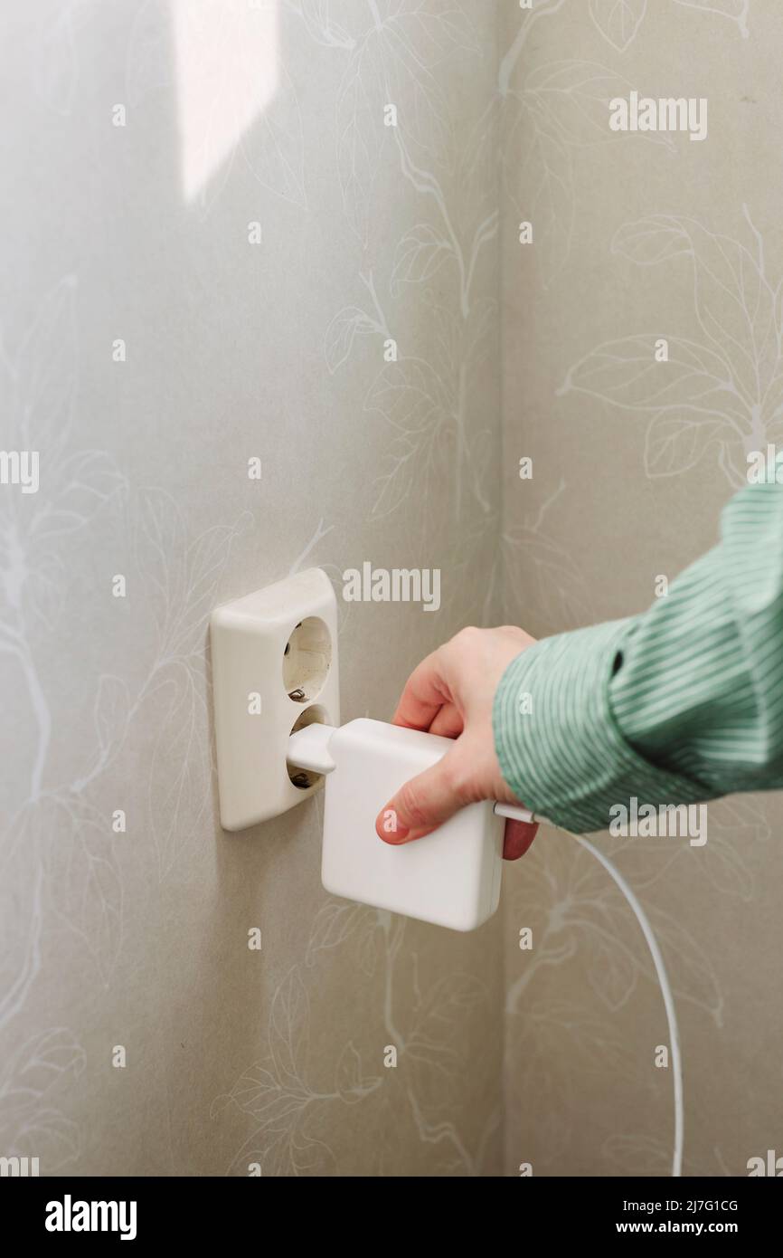 Hand plugging in or out electric cord into socket Stock Photo