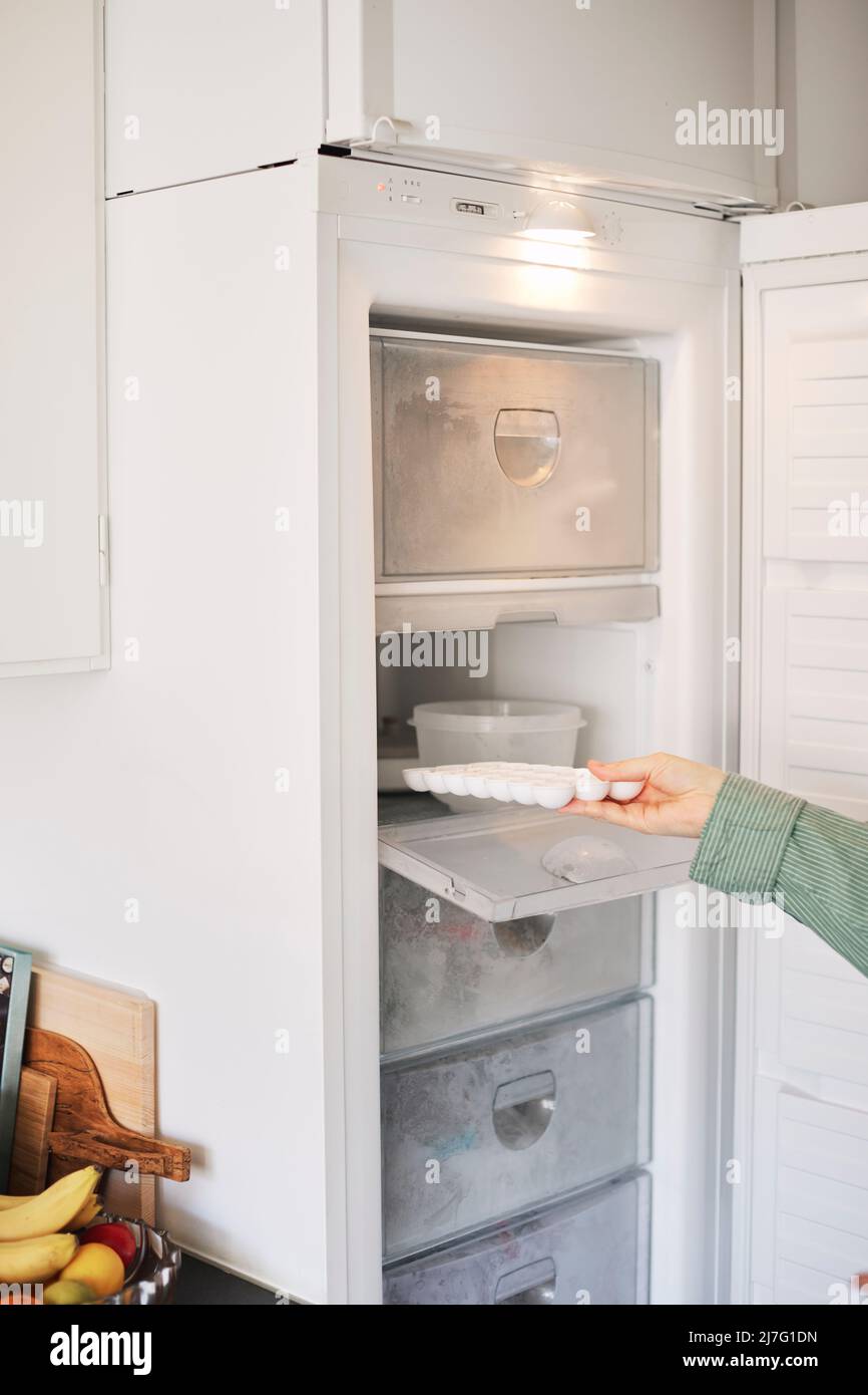 Woman's hand taking ice cubes out of freezer Stock Photo