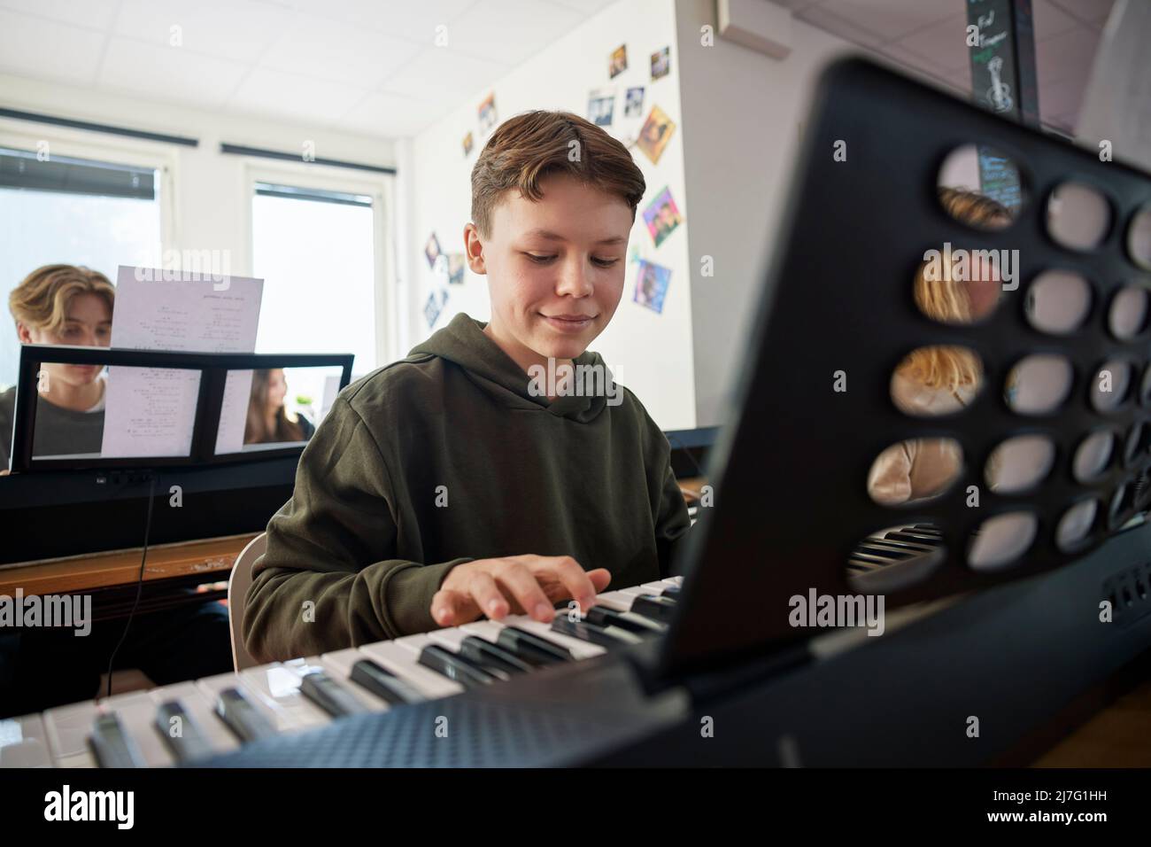 Foto de Young pianist boy looking at the digital tablet screen for learning piano  online at home. Music distance learning concept. do Stock