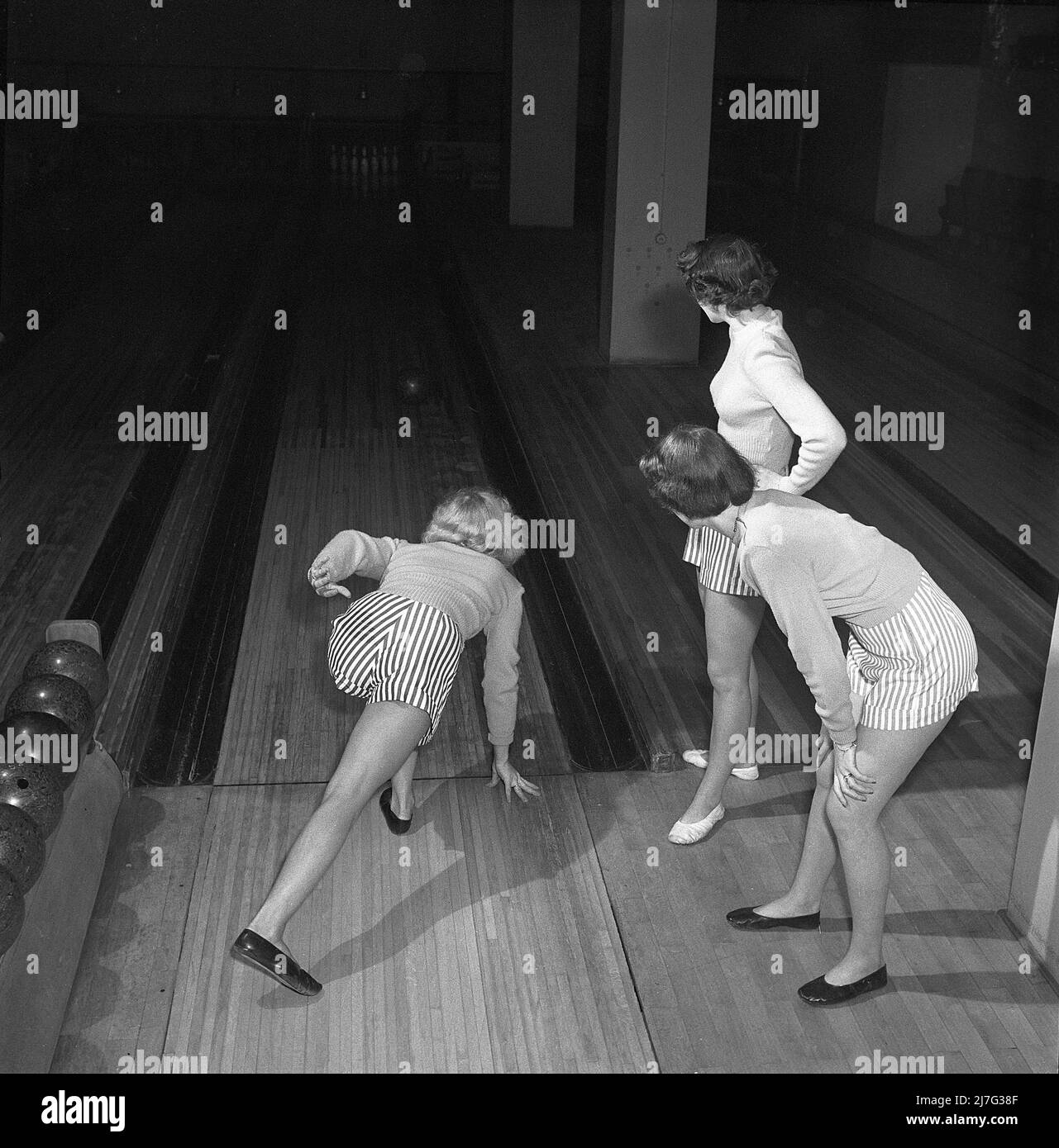 Bowling in the 1950s. Three girls are bowling for the first time ever. They are dressed in short striped skirts and jumpers. The three girls are all theatre actresses; Ingrid Björk, UllaCarin Rydén and Brita Ulfberg. 1950. Sweden Kristoffersson ref AY36-9 Stock Photo