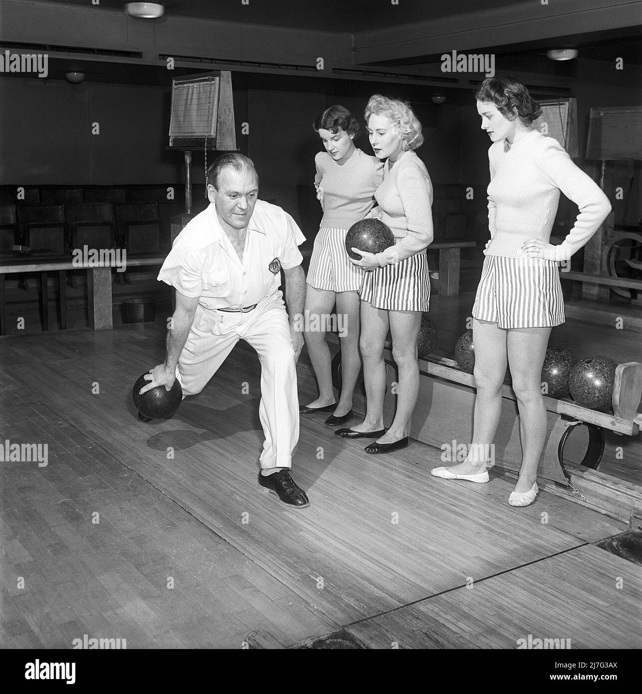 Bowling in the 1950s. A man is throwing the bowling ball and three