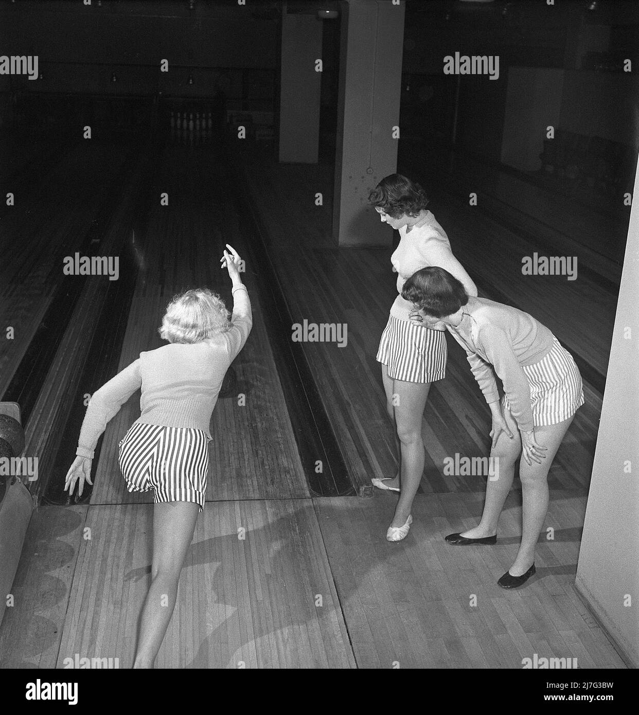 Bowling in the 1950s. Three girls are bowling for the first time ever. They are dressed in short striped skirts and jumpers. The three girls are all theatre actresses; Ingrid Björk, UllaCarin Rydén and Brita Ulfberg. 1950. Sweden Kristoffersson ref AY36-12 Stock Photo