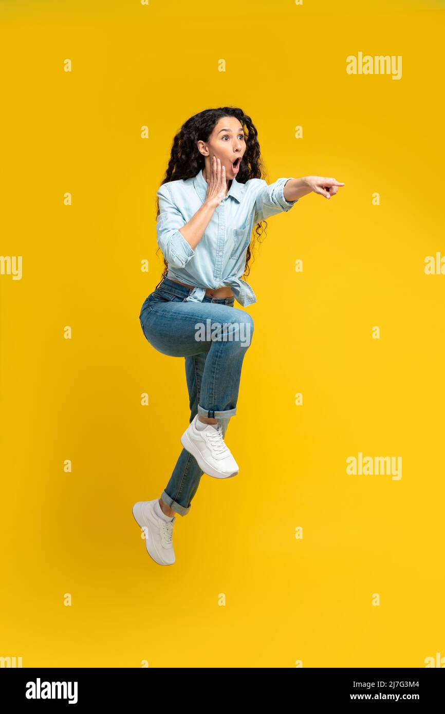 Excited woman pointing finger aside at copy space Stock Photo