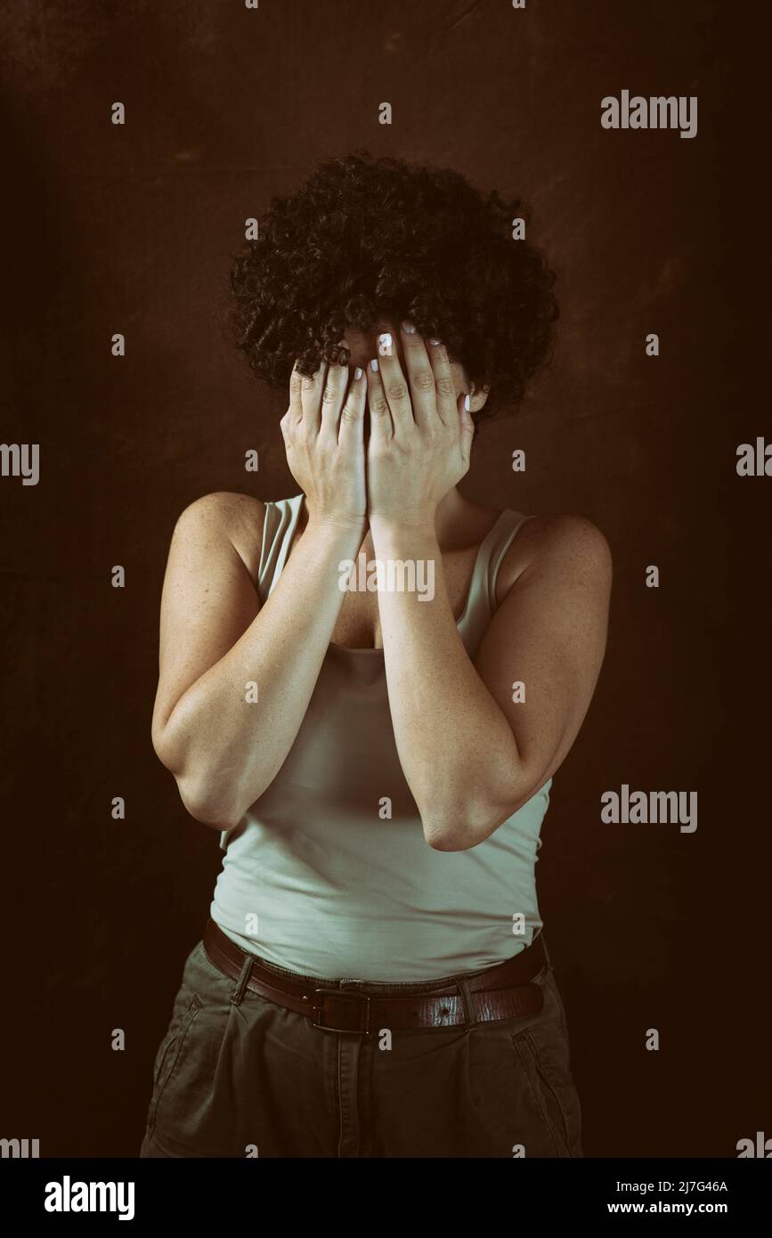 woman with short hair hiding face with hands crying outdoors Stock Photo