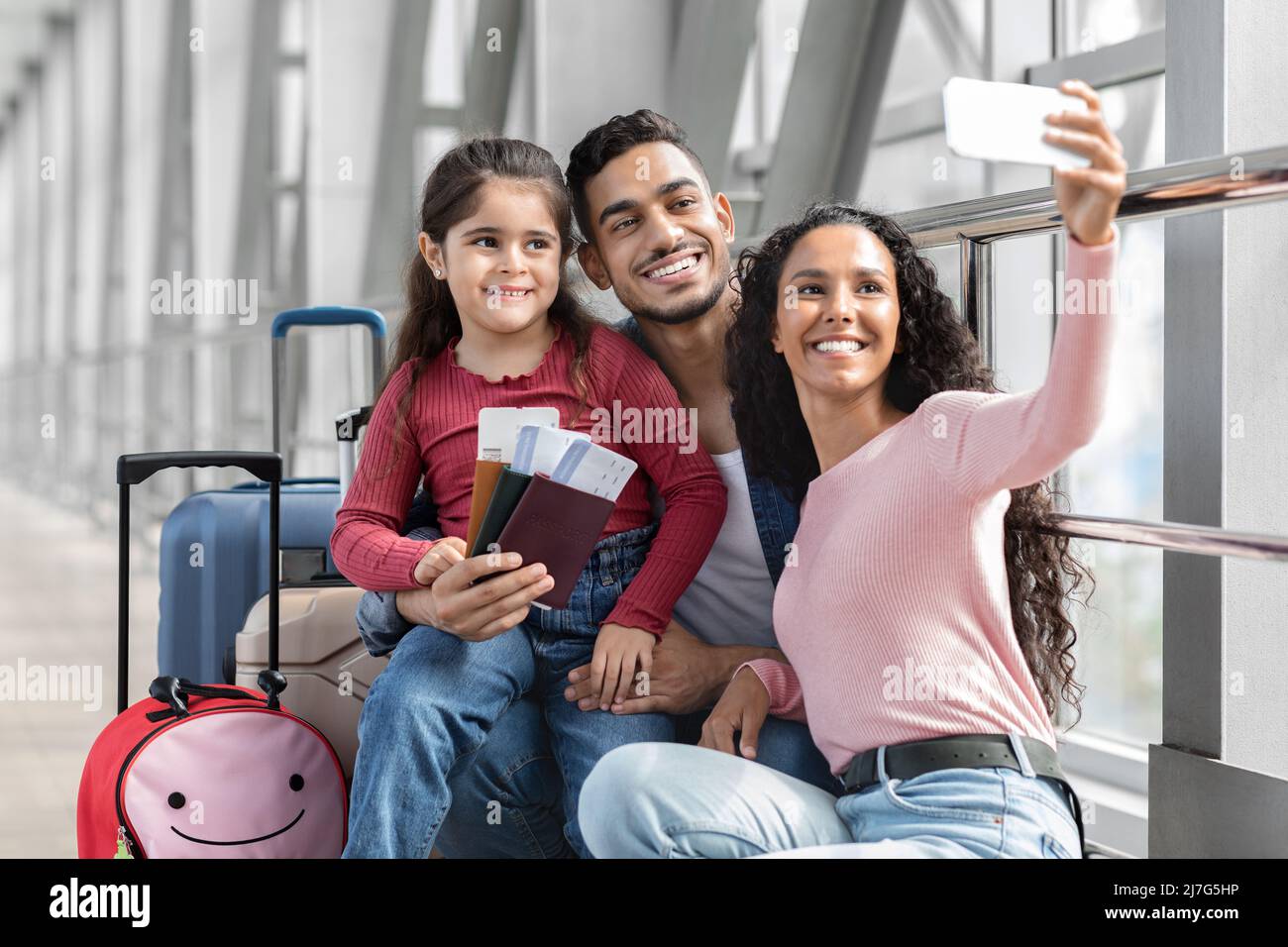 Airport Selfie . Happy Middle Eastern Family Of Three Taking Photo With Smartphone Stock Photo