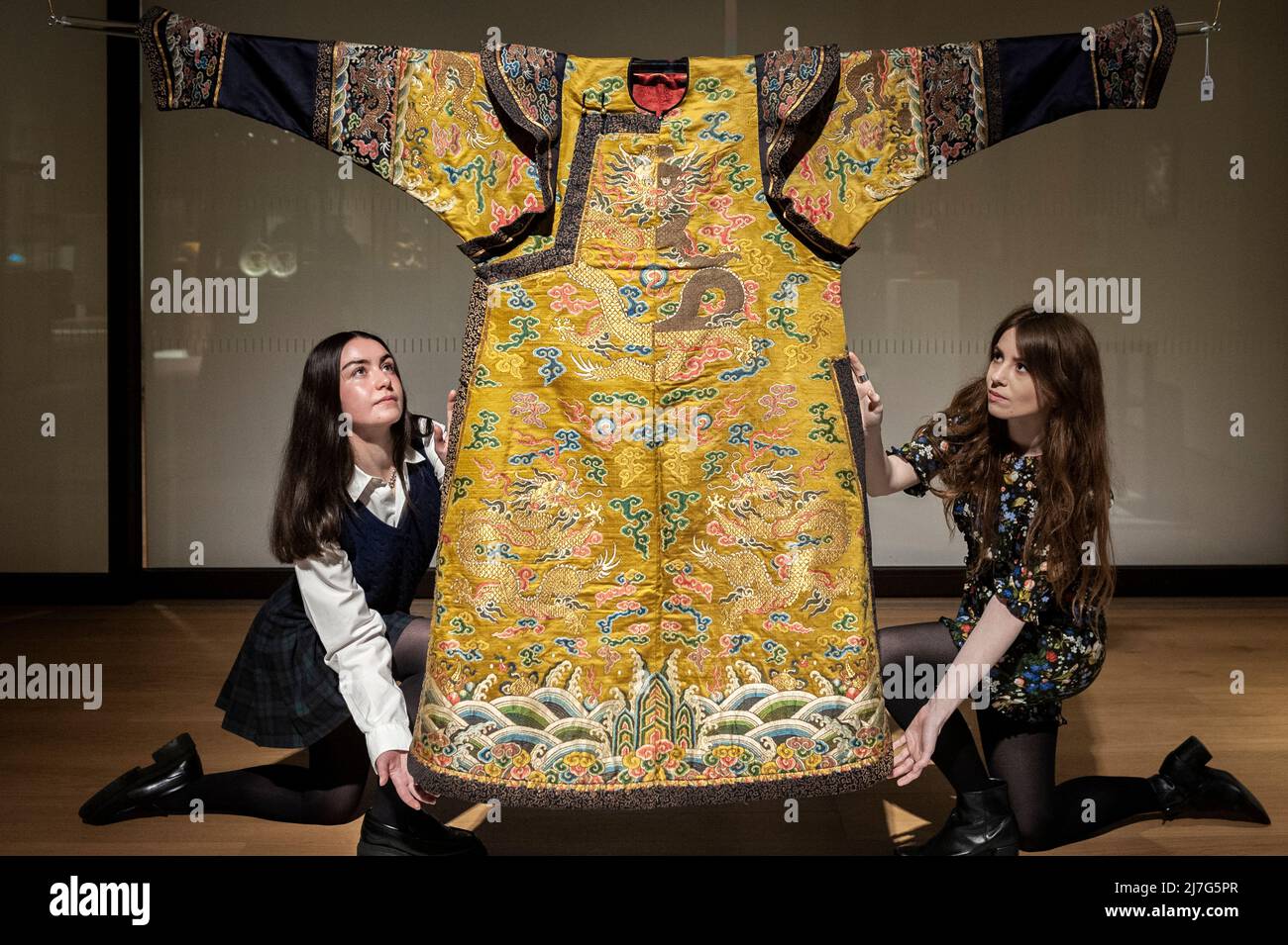 London, UK.  9 May 2022. Staff members poses with “An Exceptionally Rare Yellow-Ground Silk 'Dragon' Noblewoman's Court Robe, Chaopao”, Qianlong,, (Est. £80,000 - £120,000) at a preview of Bonhams’ Fine Chinese Art sale at their New Bond Street gallery.  Chinese jades, ceramics, lacquerware, Imperial and Court textiles and works of art will be offered for sale 12 May.  Credit: Stephen Chung / Alamy Live News Stock Photo