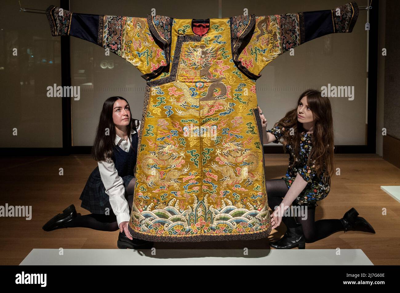 London, UK.  9 May 2022. Staff members poses with “An Exceptionally Rare Yellow-Ground Silk 'Dragon' Noblewoman's Court Robe, Chaopao”, Qianlong,, (Est. £80,000 - £120,000) at a preview of Bonhams’ Fine Chinese Art sale at their New Bond Street gallery.  Chinese jades, ceramics, lacquerware, Imperial and Court textiles and works of art will be offered for sale 12 May.  Credit: Stephen Chung / Alamy Live News Stock Photo