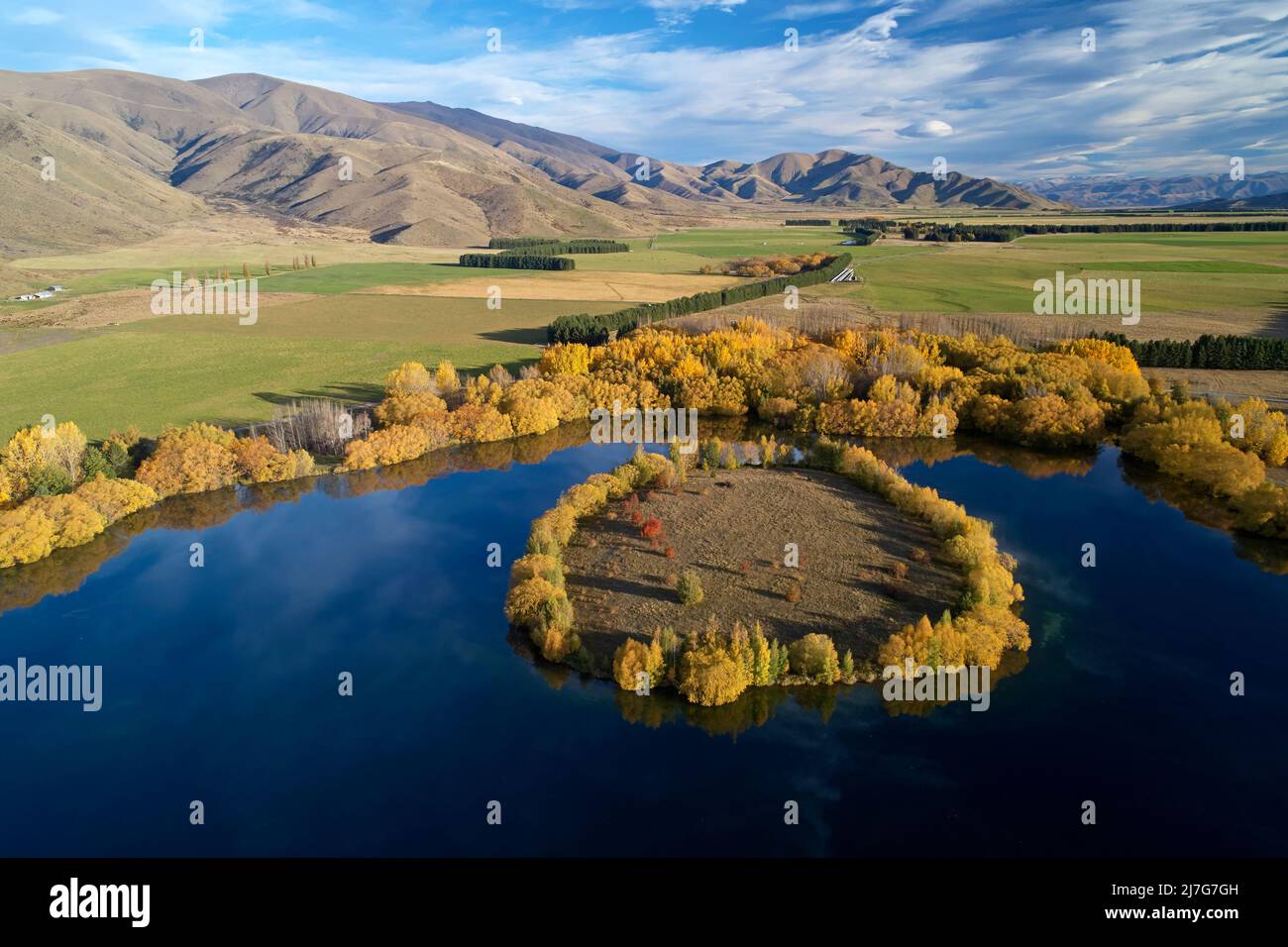 Autumn colours and island in Wairepo Arm, Twizel, Mackenzie District, North Otago, South Island, New Zealand - drone aerial Stock Photo