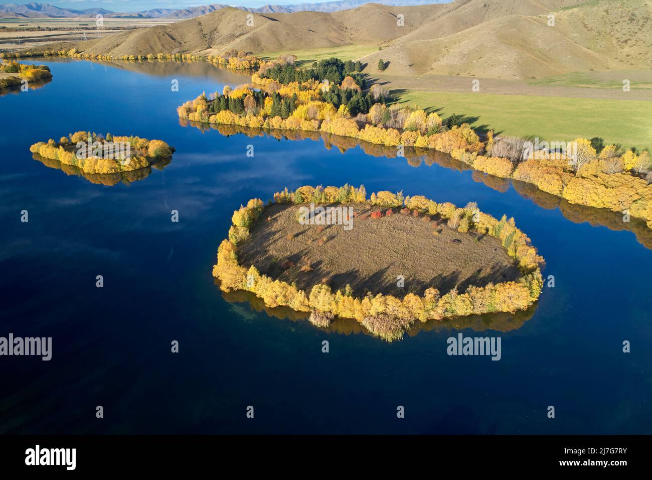 Autumn colours and islands in Wairepo Arm, Twizel, Mackenzie District, North Otago, South Island, New Zealand - drone aerial Stock Photo