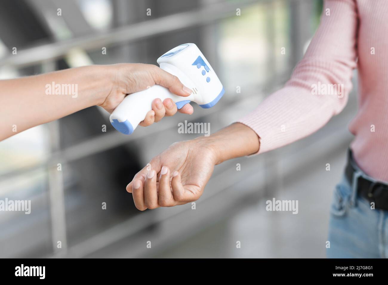 Temperature Control. Security Stuff Using Electronic Medical Thermometer To Female At Airport Stock Photo
