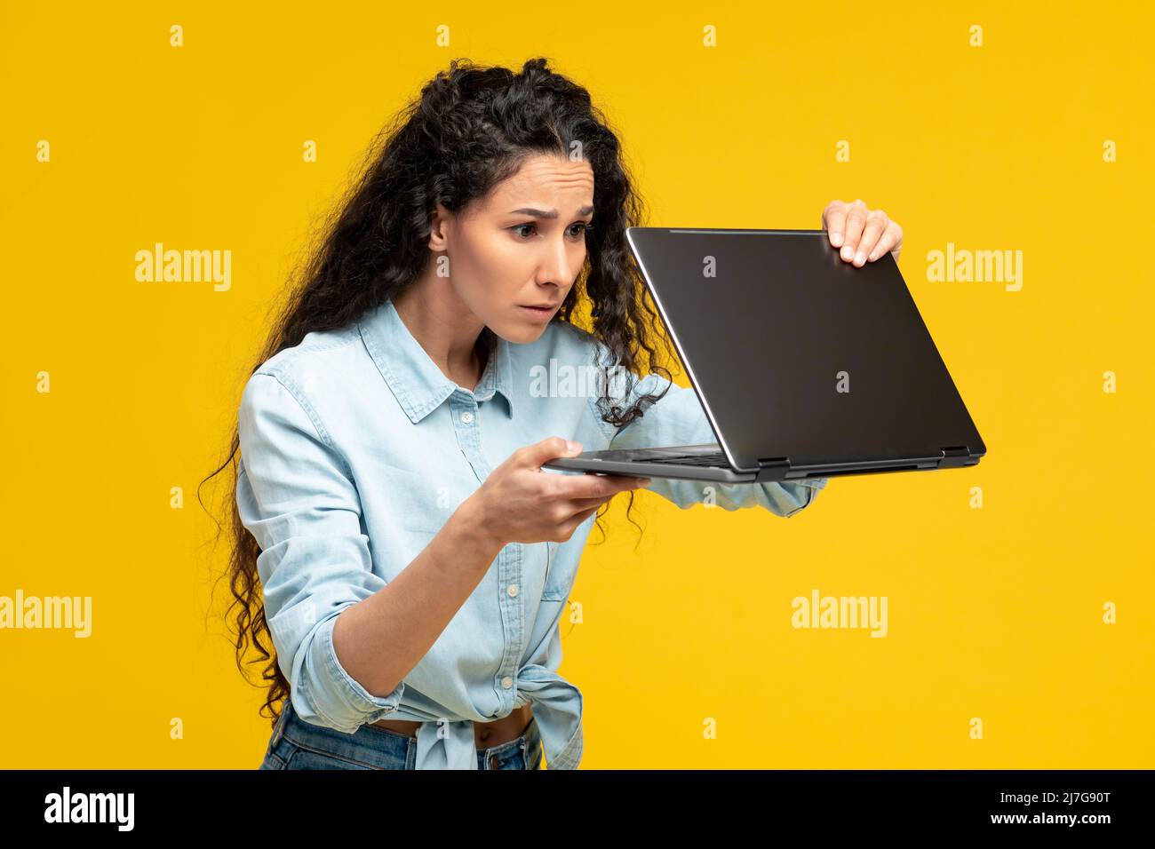 Scared young woman using laptop at studio Stock Photo
