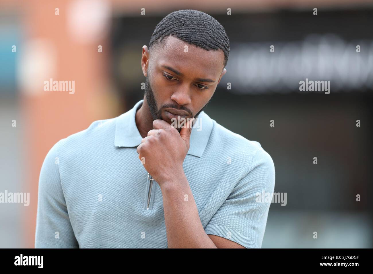 Front view portrait of a pensive man with black skin walking alone in the street Stock Photo
