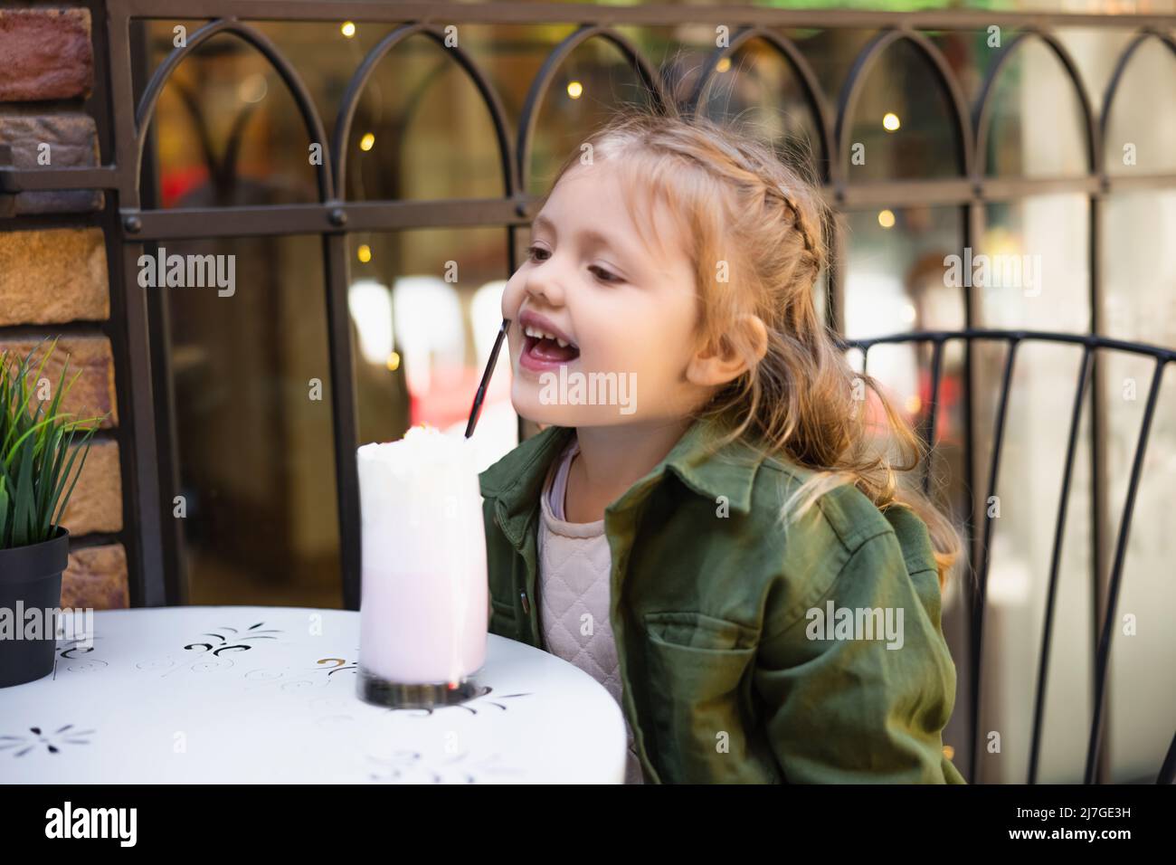 https://c8.alamy.com/comp/2J7GE3H/happy-child-reaching-straw-in-glass-of-tasty-milkshake-outdoors-2J7GE3H.jpg