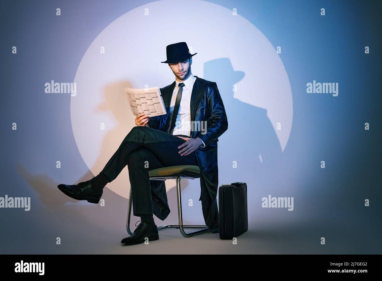 Handsome private detective sitting on chair reading newspaper in the