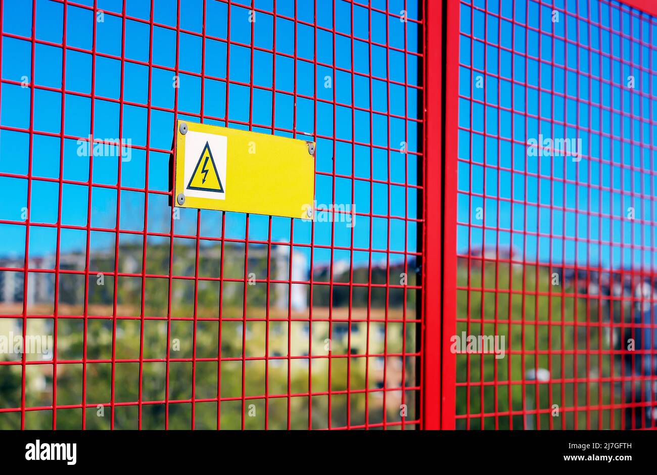 High voltage warning sign hanging from the red grille somewhere in Poland Stock Photo