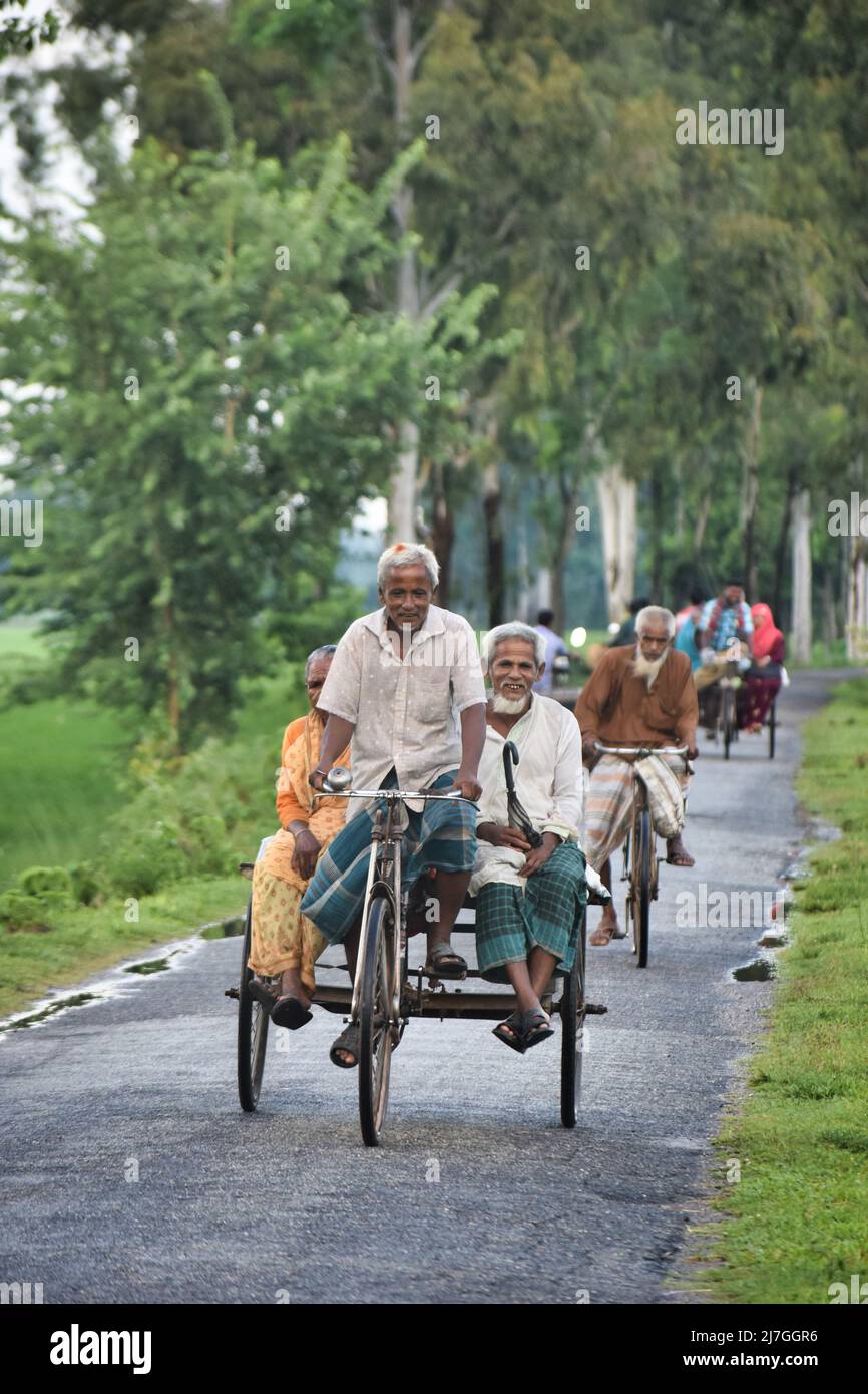 Dinajpur, Bangladesh - July 9, 2021: A happy old man driving a van which is the local traveling system of the village people in Bangladesh. Stock Photo