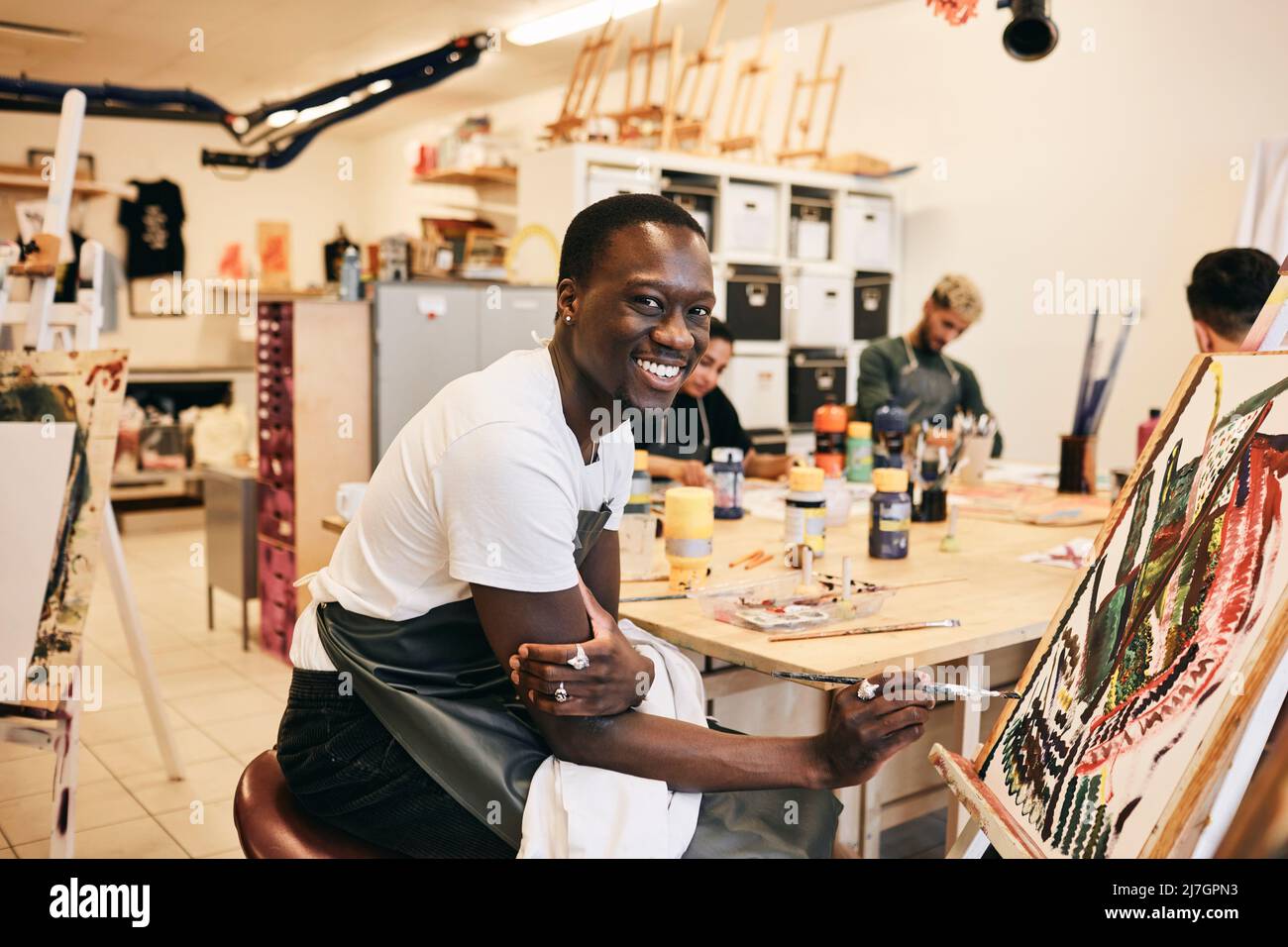 Portrait of smiling young male student painting on artist's canvas in art class Stock Photo