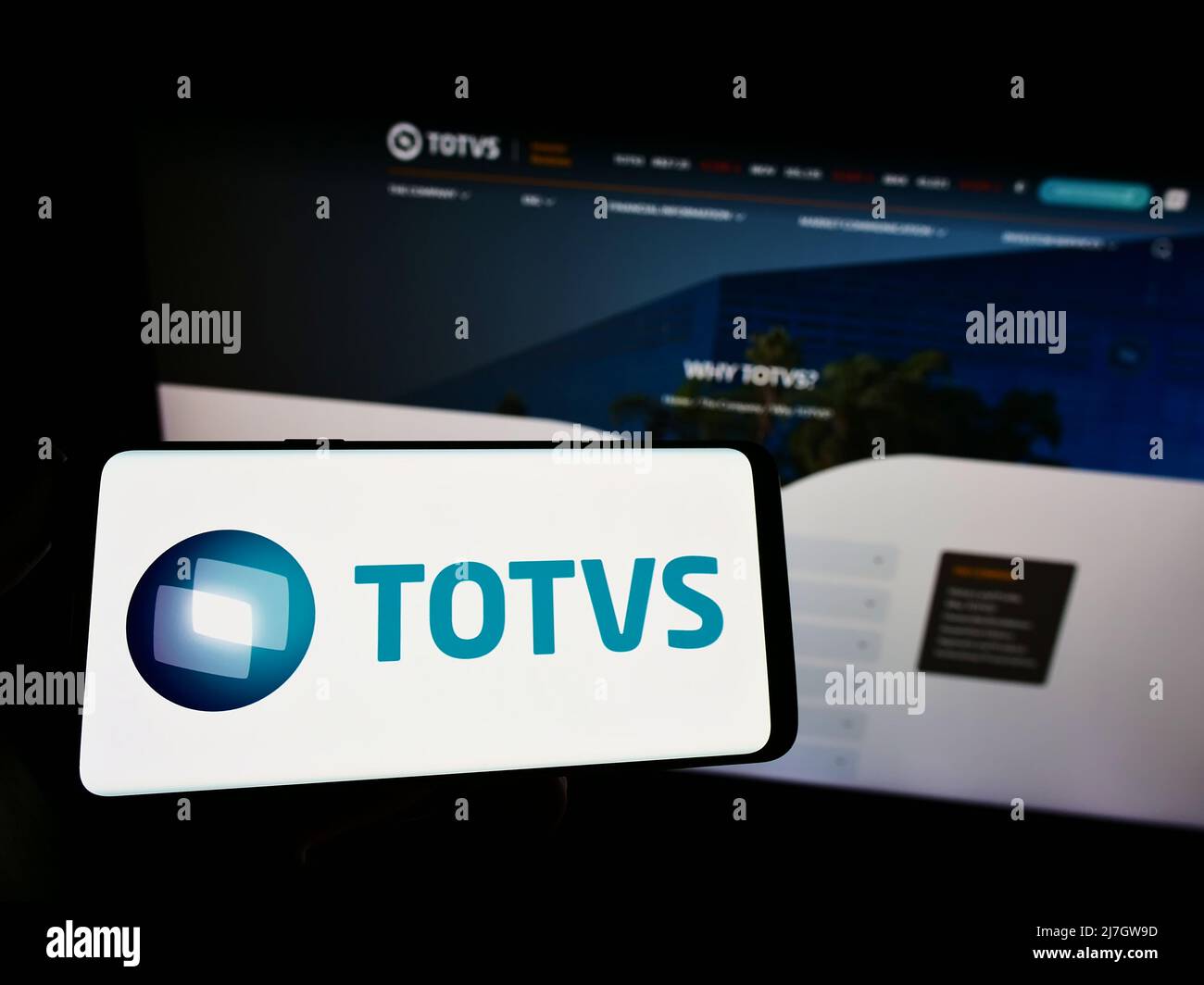 Person holding smartphone with logo of Brazilian software company TOTVS S.A. on screen in front of website. Focus on phone display. Stock Photo