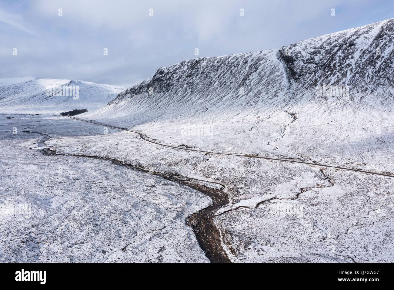 Stunning aerial drone panorama landscape image of Stob Dearg and Glencoe in Scottish Highlands during deep snowfall and beautiful blue skies Stock Photo