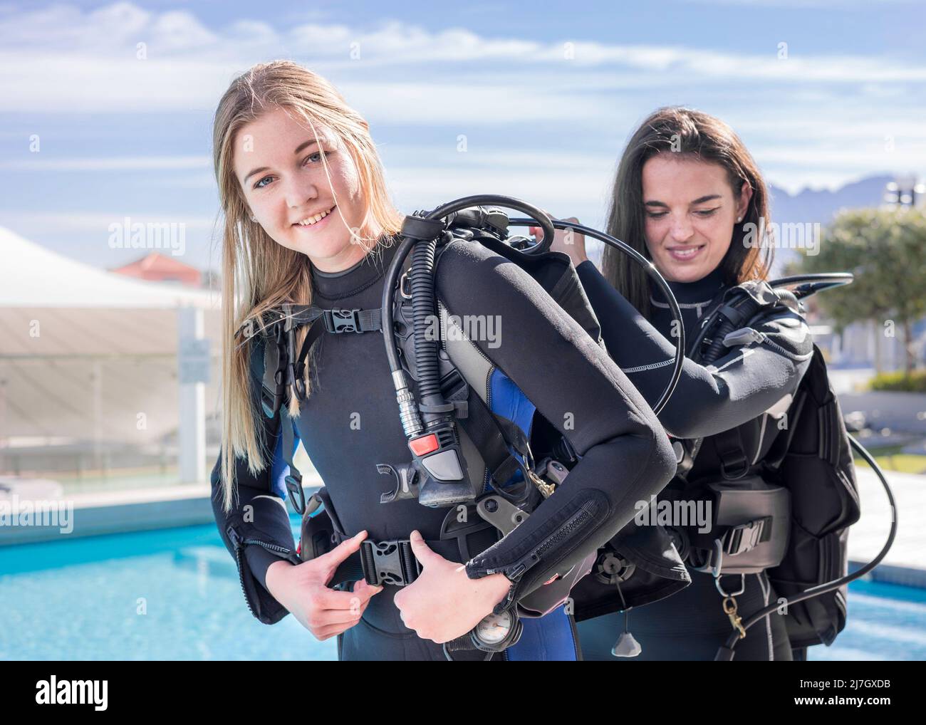 Scuba divers helping each other to put their gear on next to a pool Stock Photo