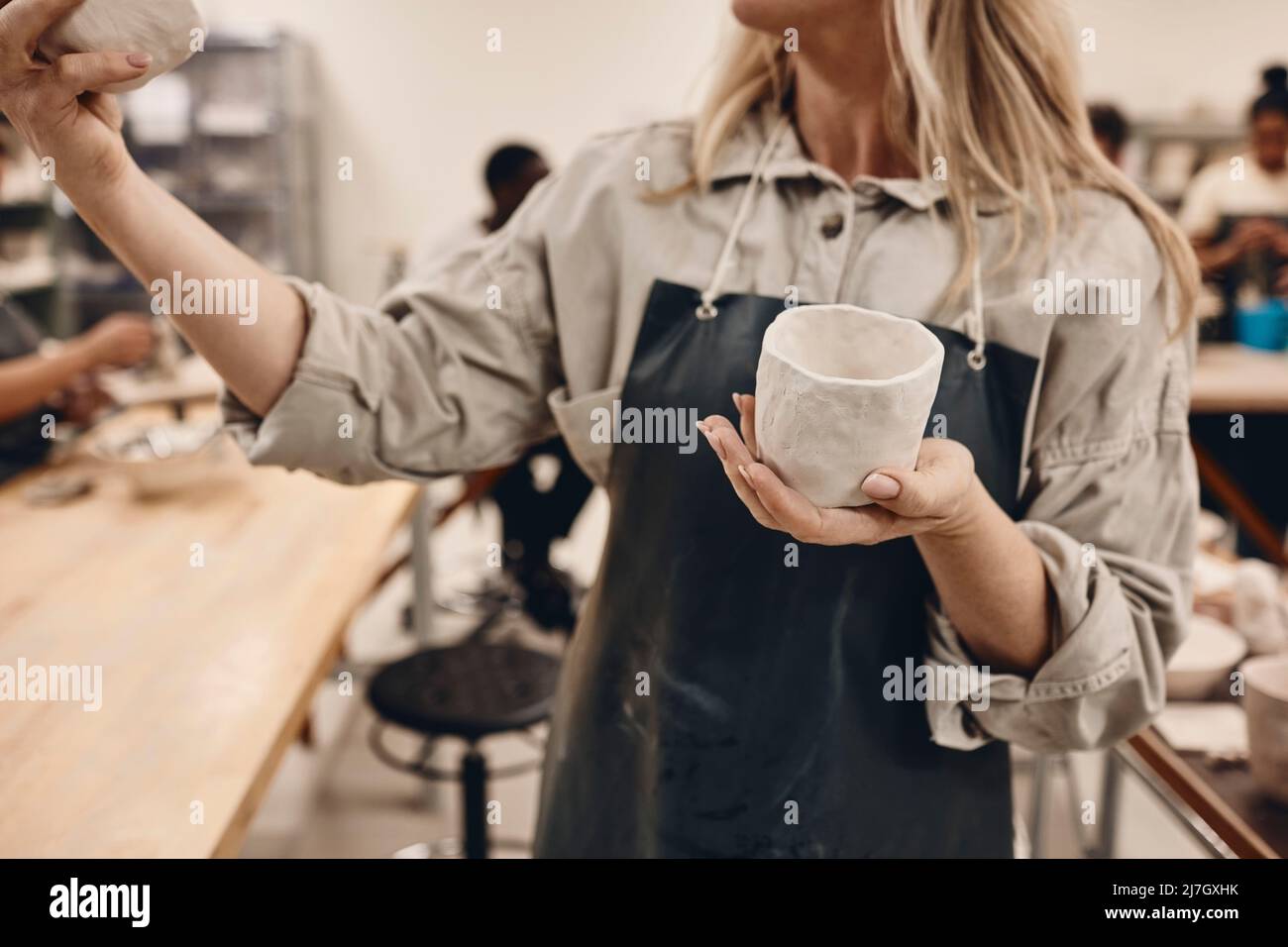 Midsection of mature woman examining ceramics in art class Stock Photo