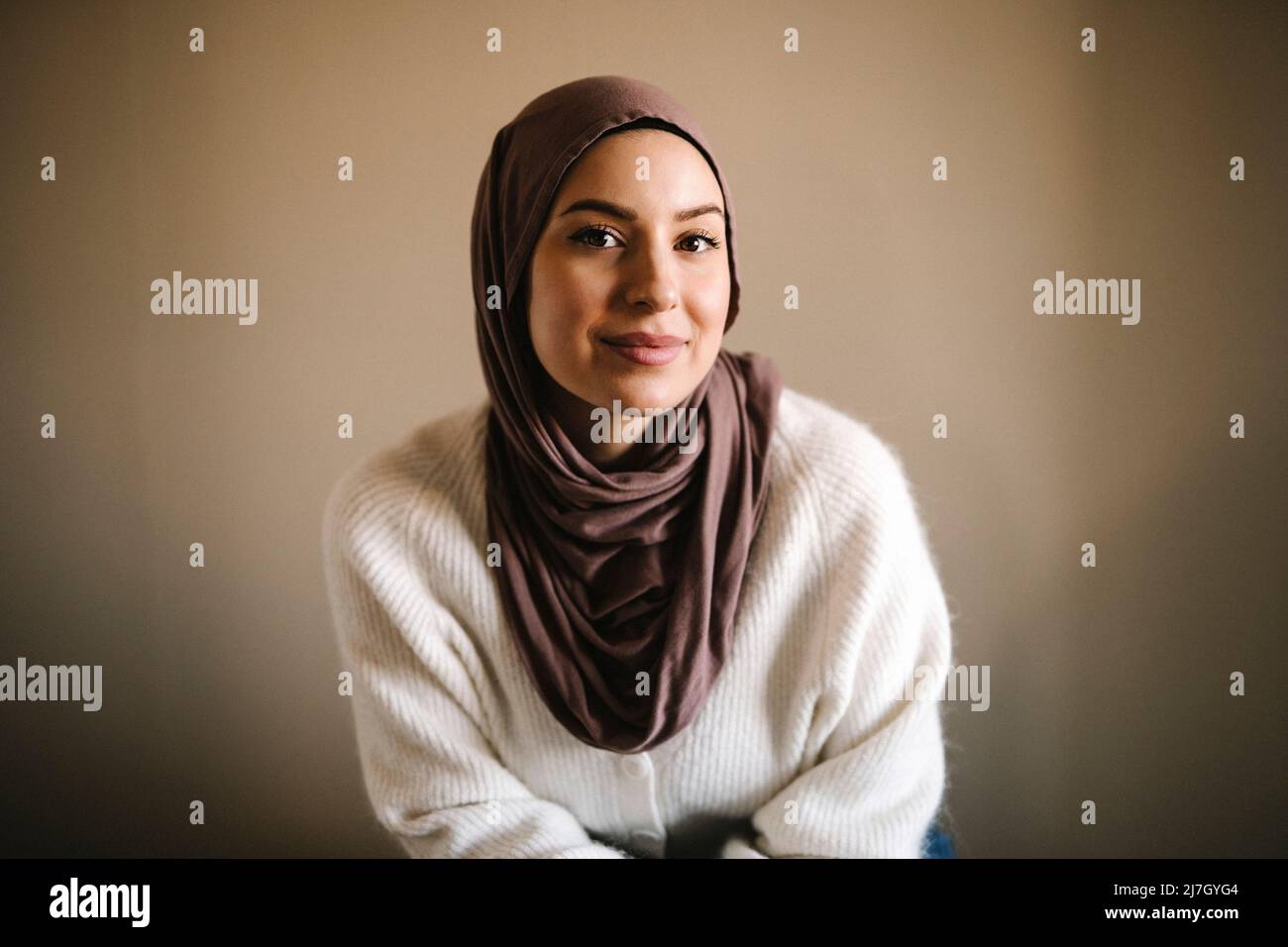 Smiling young woman in hijab against beige background Stock Photo - Alamy