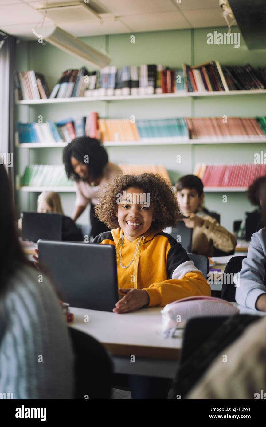 Smiling girl with laptop at desk in classroom Stock Photo - Alamy