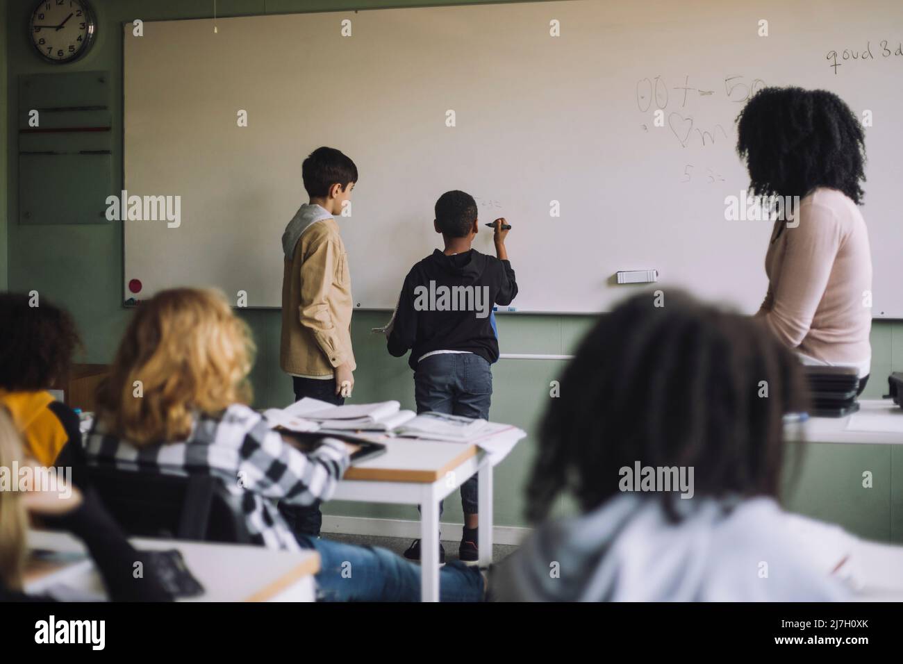 Students solving maths sum on white board in classroom Stock Photo