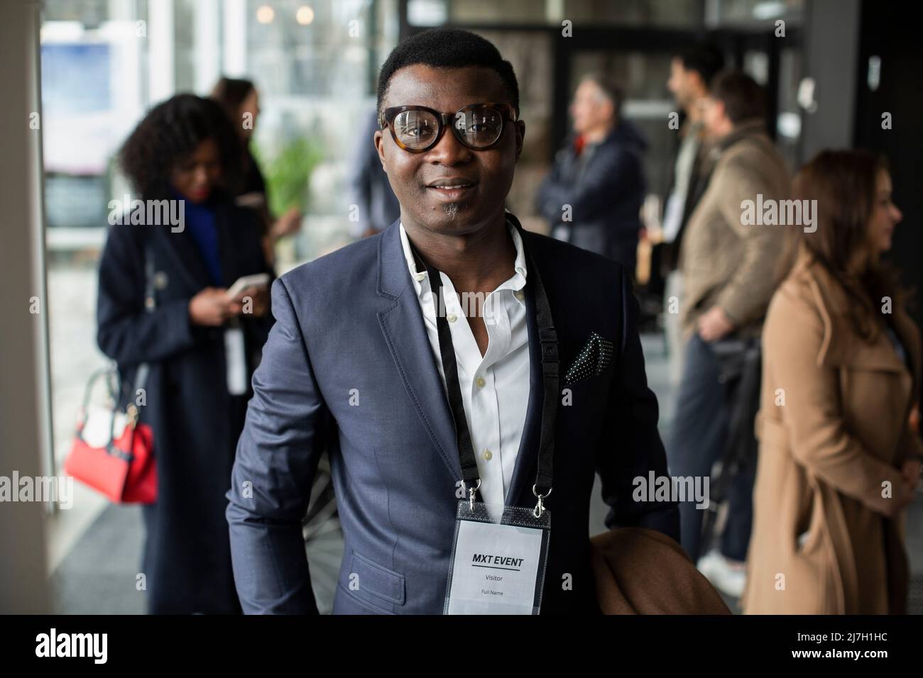 Businessman wearing ID card standing in lobby of conference center Stock Photo