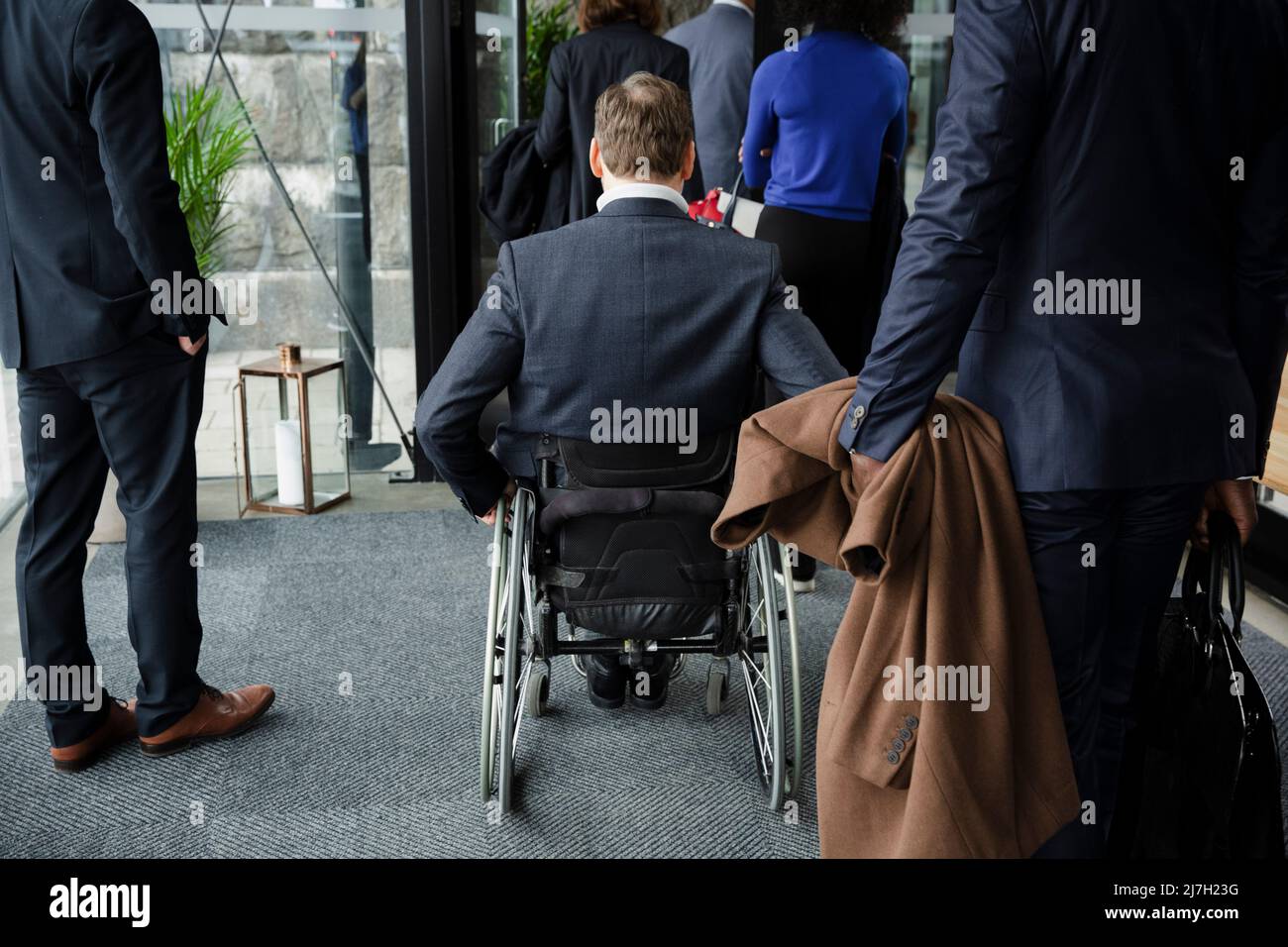 Rear view of disabled businessman with delegates entering conference center Stock Photo