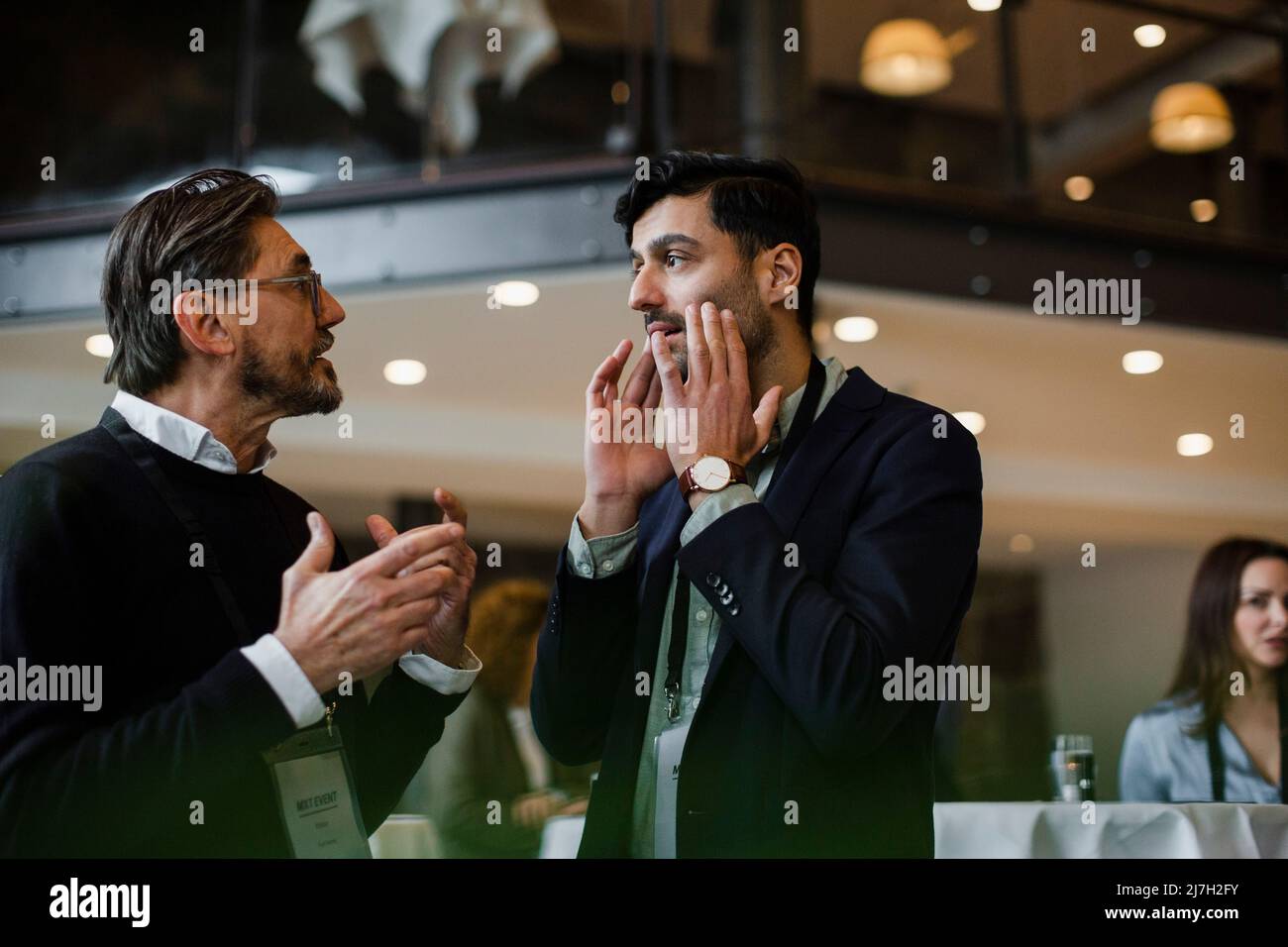 Businessmen gesturing while talking with each other during seminar Stock Photo