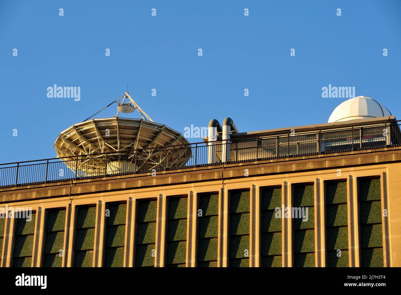 Building with astronomical radio telescope antenna and dome on rooftop