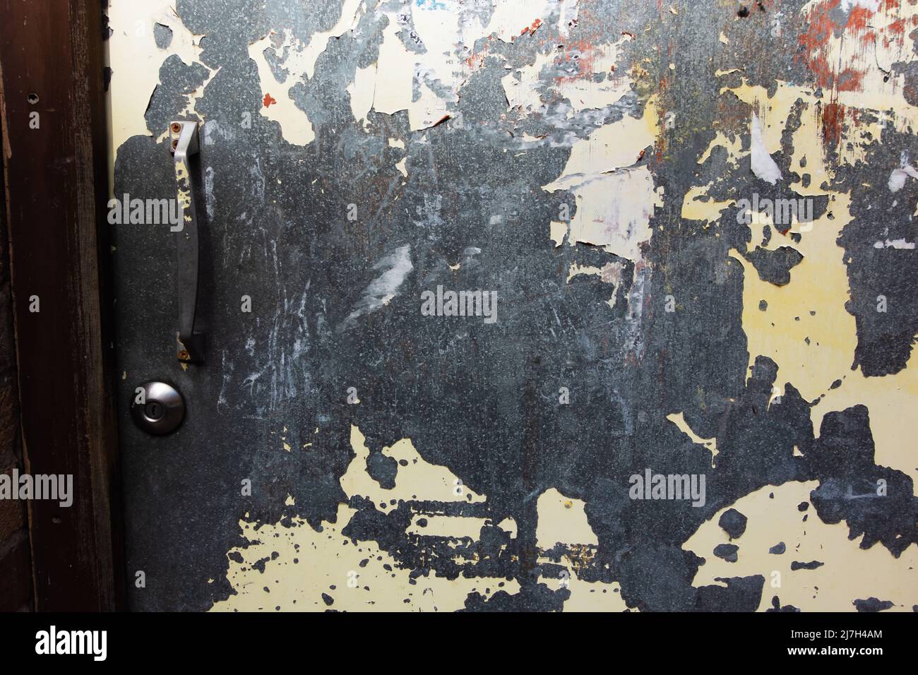 detail of a scratched steel door with lock and handle with peeling white paint Stock Photo
